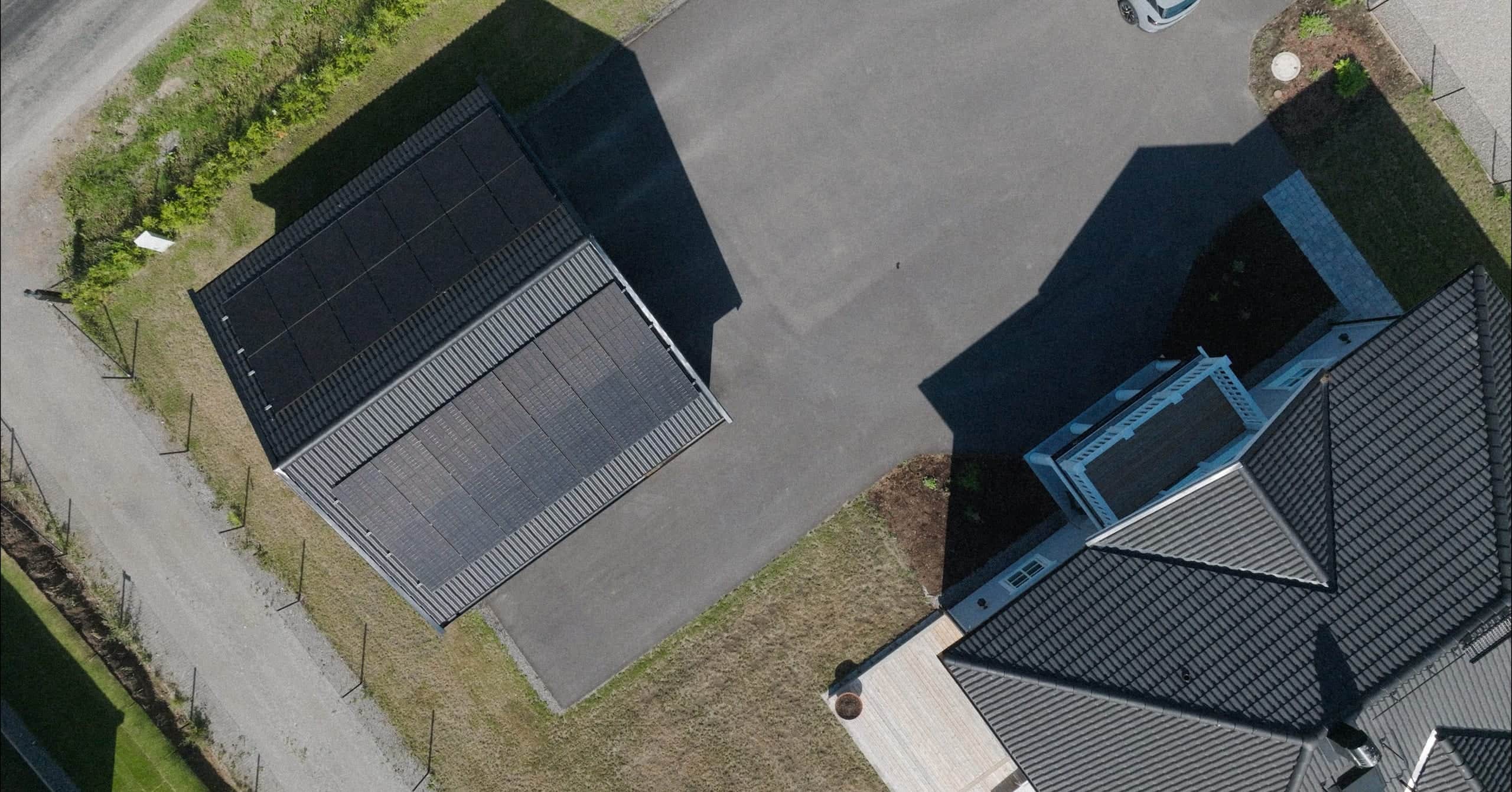 Drönarbild över solceller på ett carporttak i ett bostadsområde