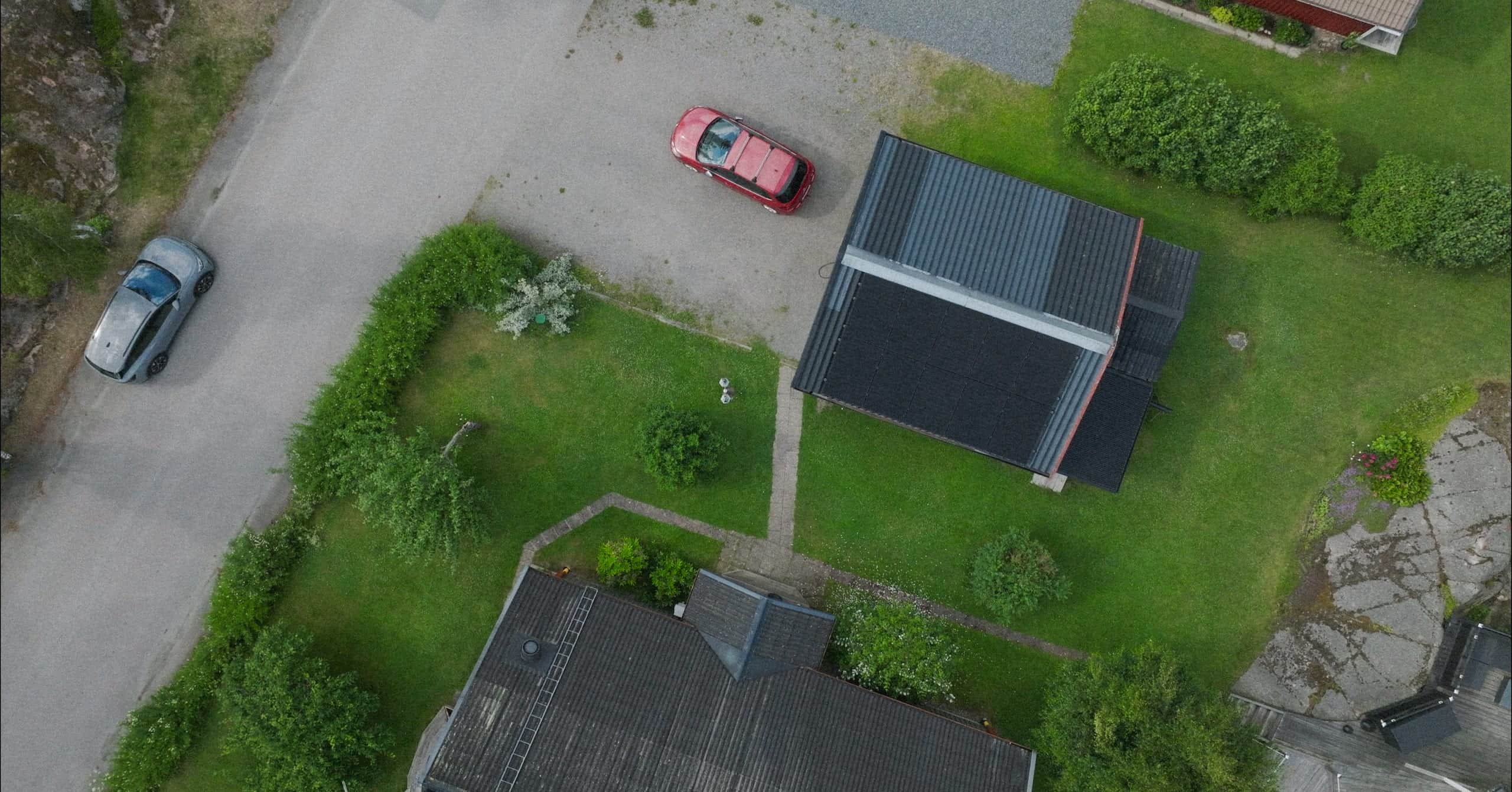 Drönarbild över en villa med solceller och uppfart i ett bostadsområde